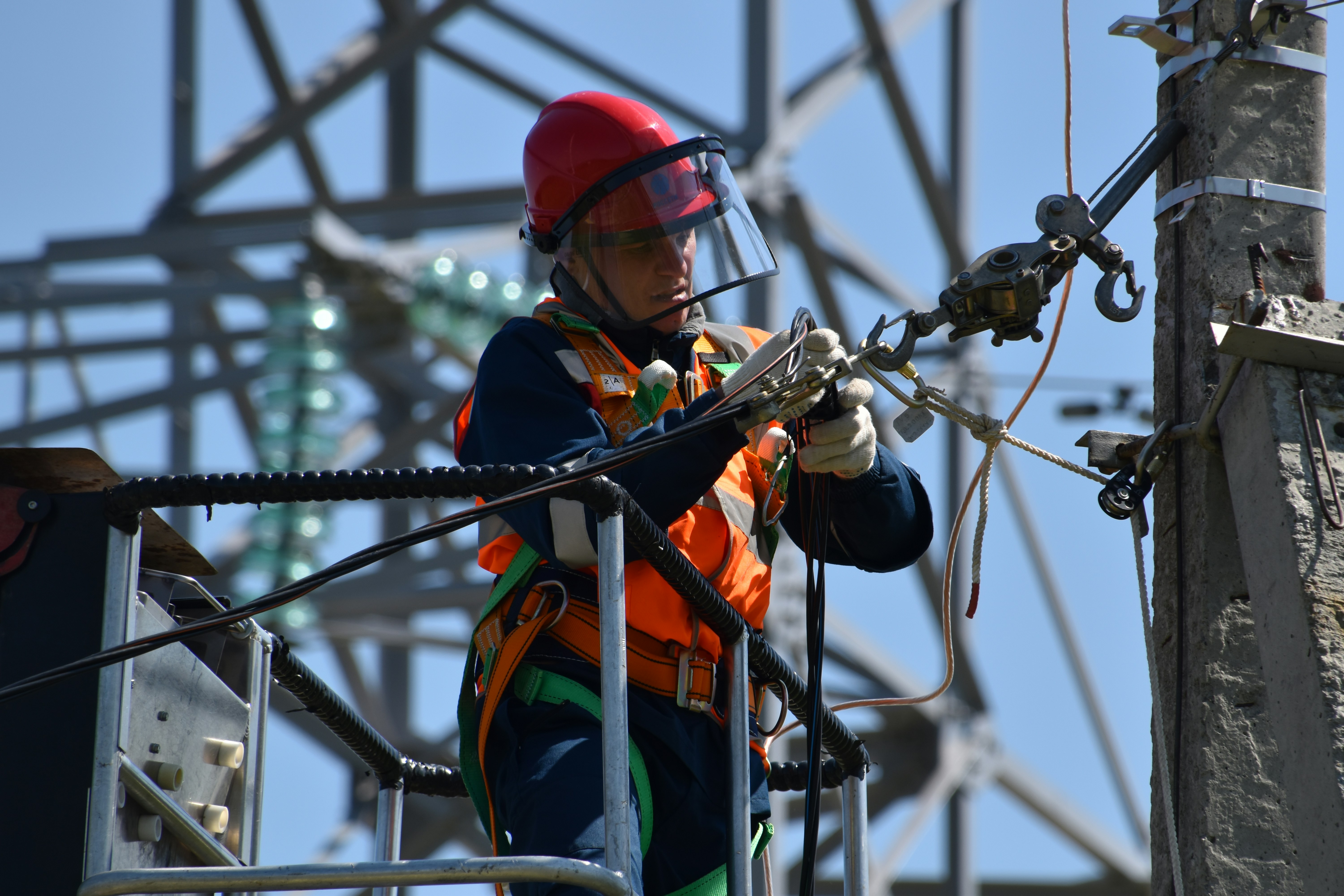 Utility lineworker performing maintenance on transmission tower